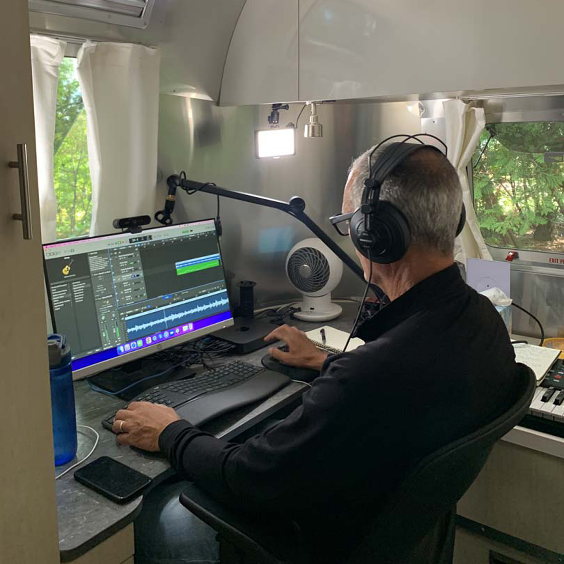 A man sitting in the Airstream Flying Cloud Office writing music.