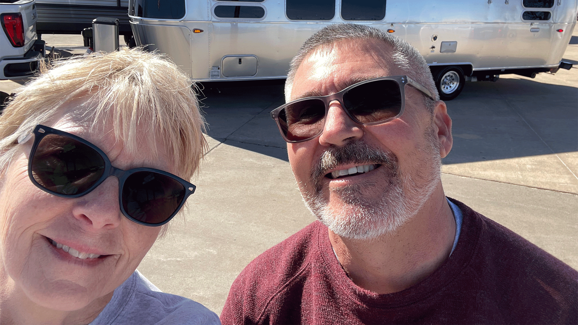 Jim and Susan taking a picture with their new Airstream International camper while they are at the dealership.