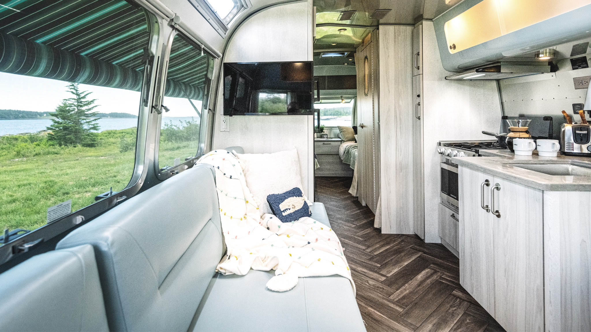 The interior of the International Airstream Travel Trailer with aqua seating and twin beds in the bedroom.