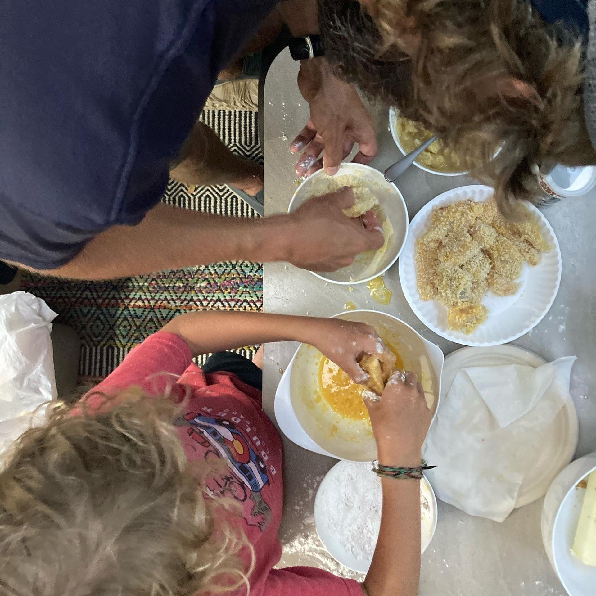 Two people sitting at a table cooking fish that they just caught.