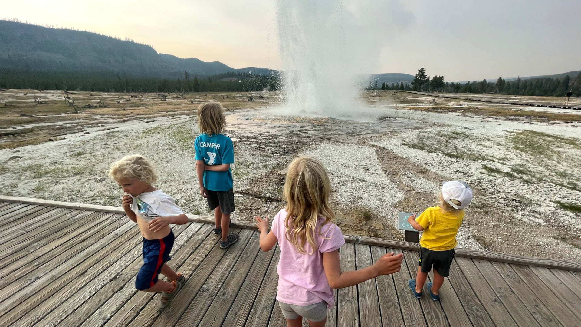 Four kids watching a geyser while they camp.