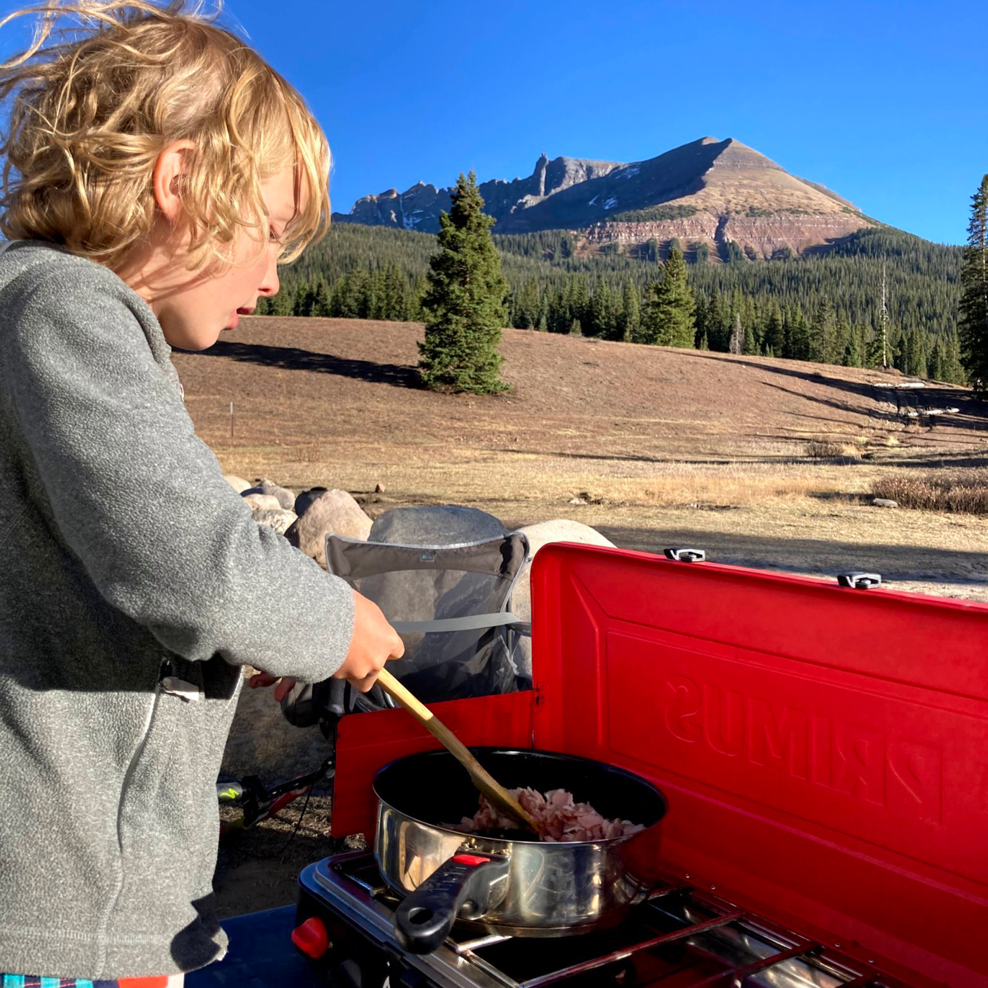 一个孩子在他的气流旅行拖车里露营时在烤架上做炒饭