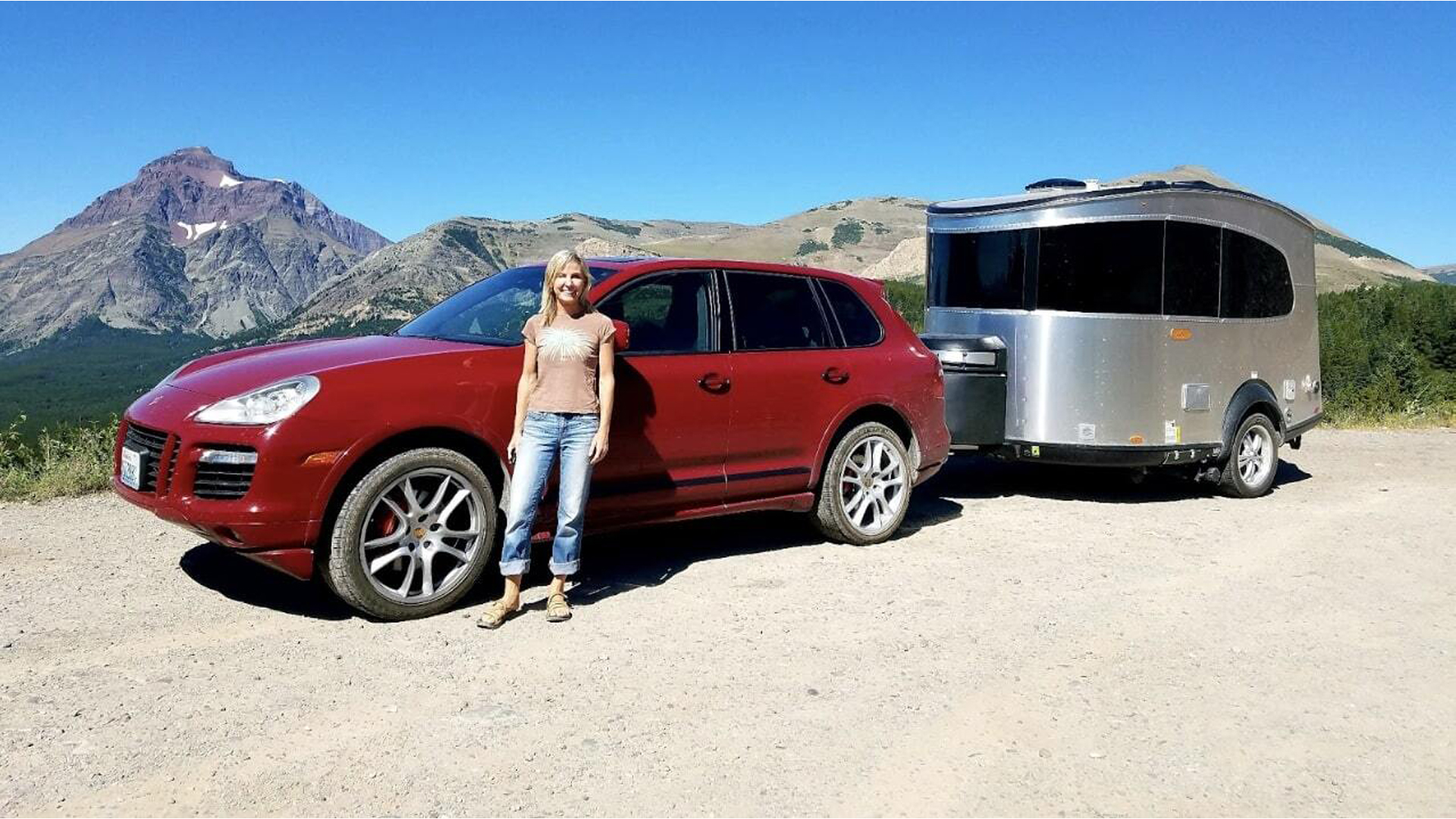 Andrea Umbach standing next to her Airstream Basecamp travel trailer that is hooked up to her red truck.