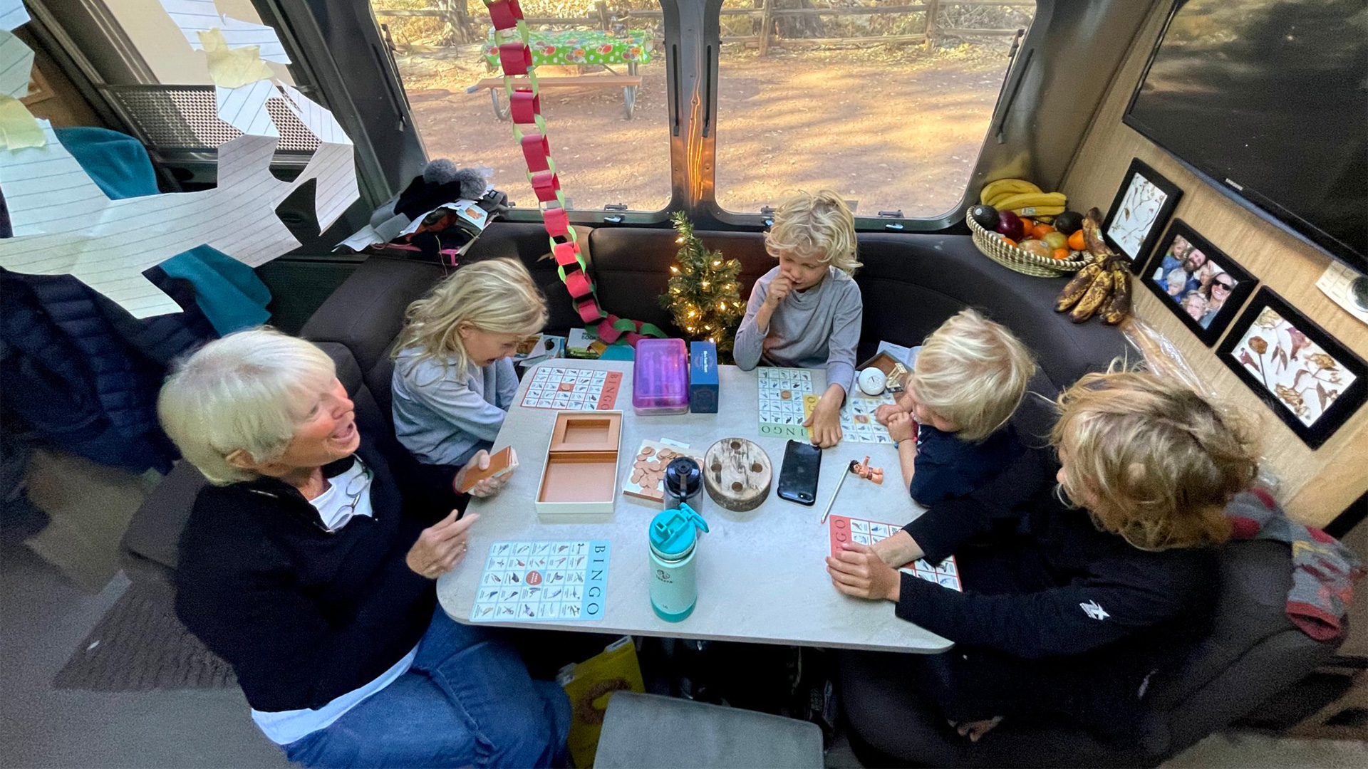 Four kids and their grandma playing Bingo and games in their Airstream travel trailer while they camp.