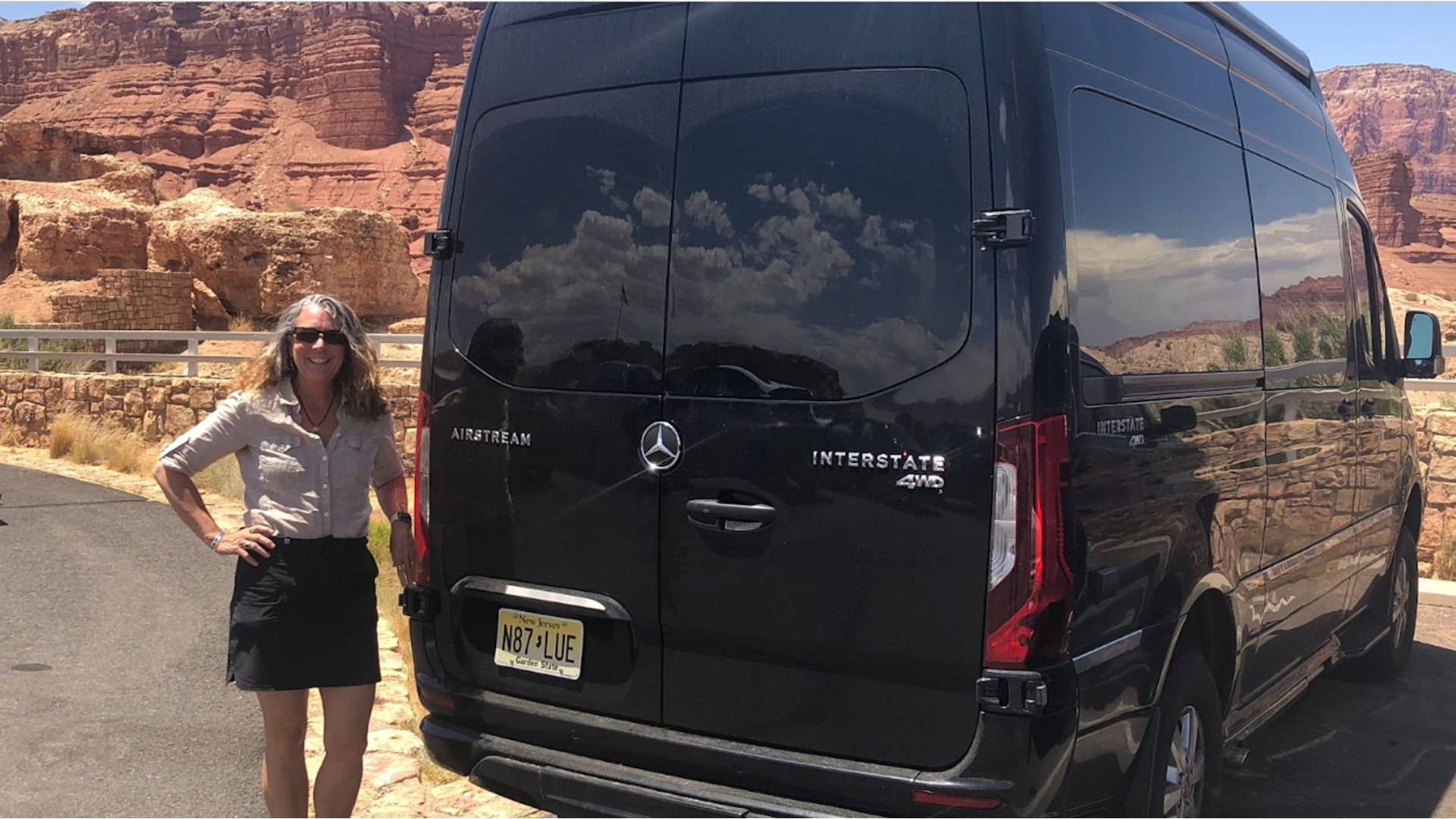 Christine Miller standing next to her black Airstream 19 Class B Motorhome that is parked in the desert.