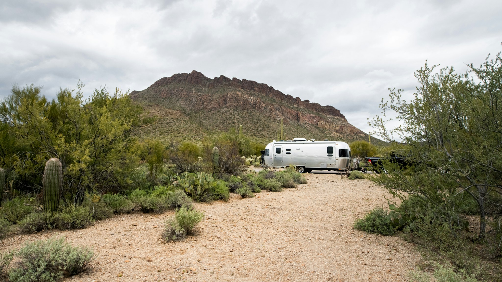 An Airstream boondocking in the dessert and is hooked up to a truck.