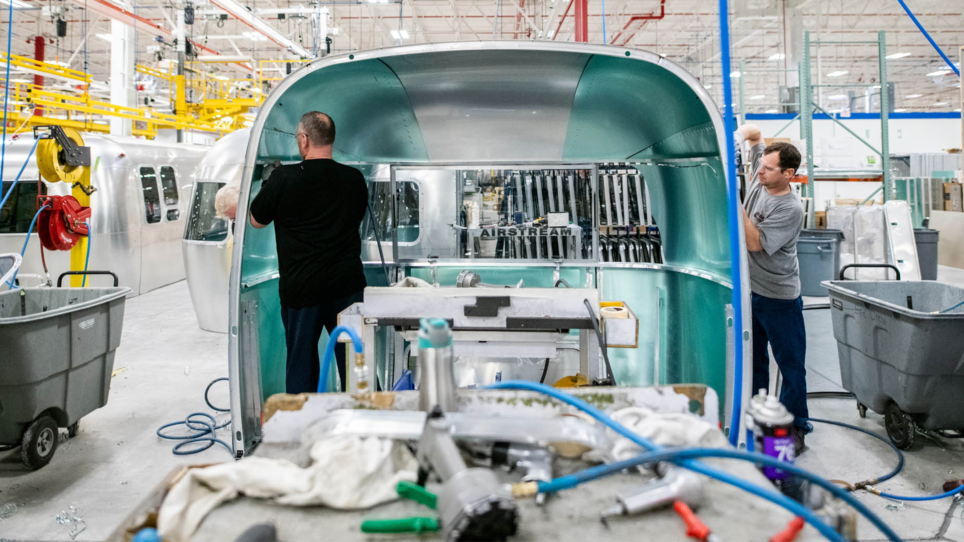 Two Airstream employees working together to build the shell of an Airstream travel trailer in Jackson Center, OH.