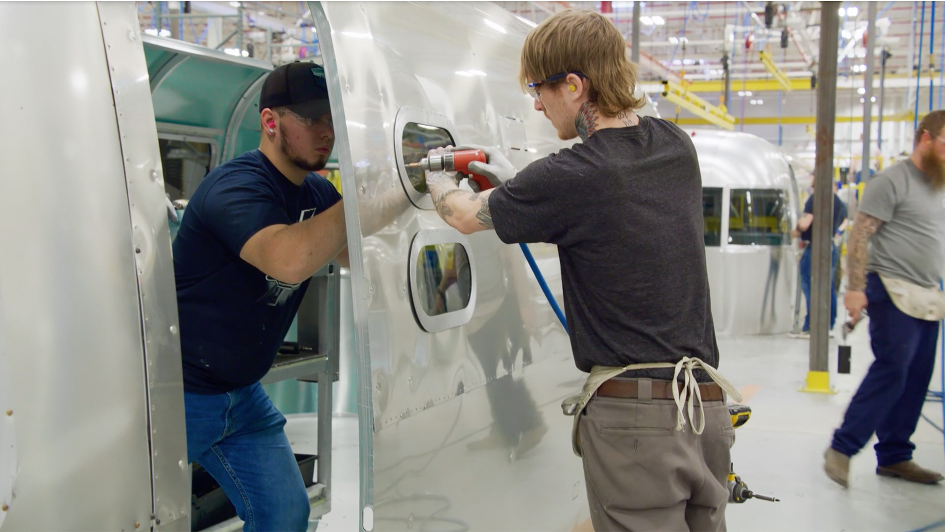 Two Airstream employees working together to rivet an Airstream travel trailer together.