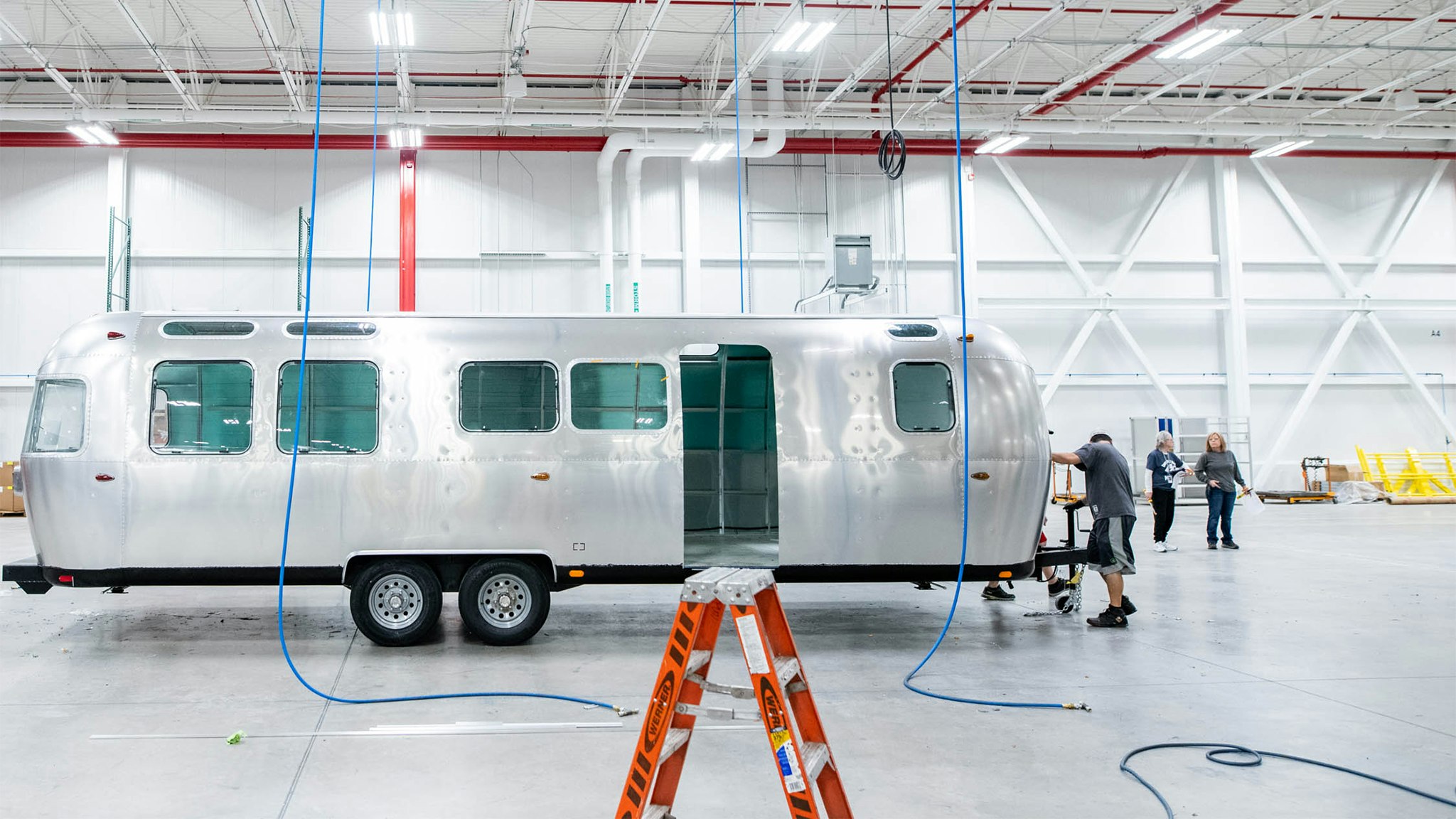 Airstream employees working on the shell of an Airstream Globetrotter travel trailer.