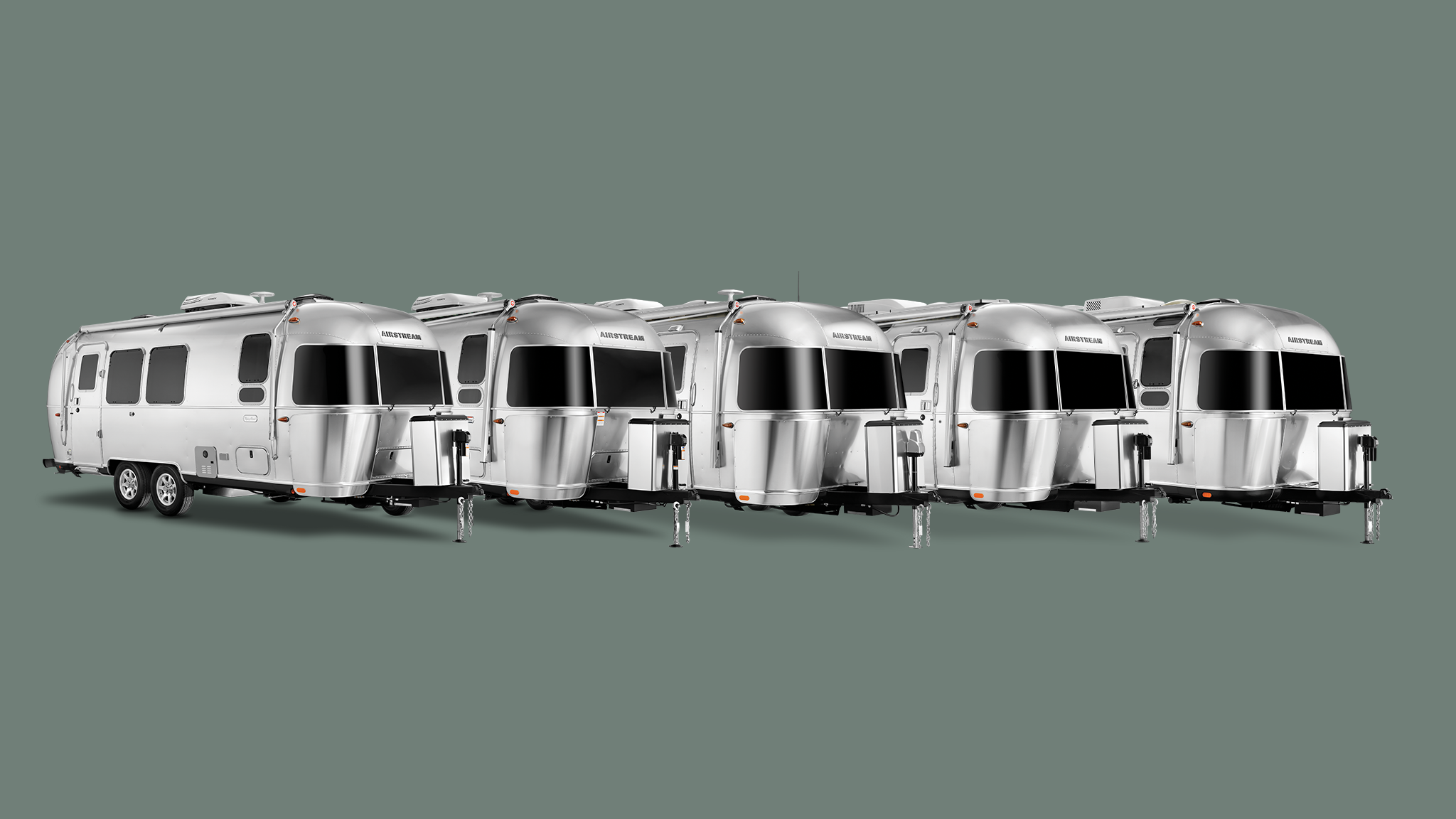 All of Airstream's dual axle travel trailers lined up in a line on a green background.