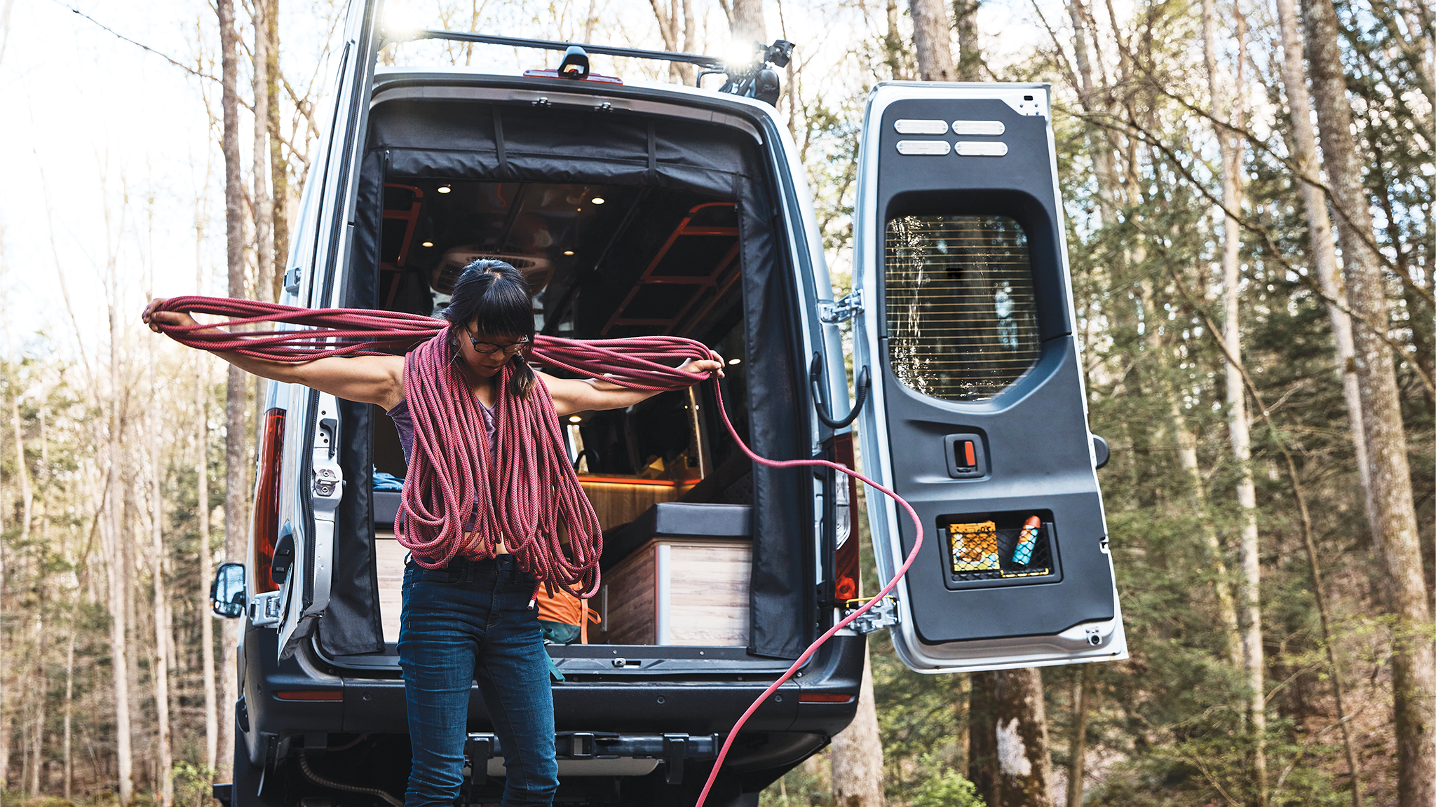 A woman getting her rope ready for a climb with her gear in her Airstream 24X Class B Motorhome in West Virgina