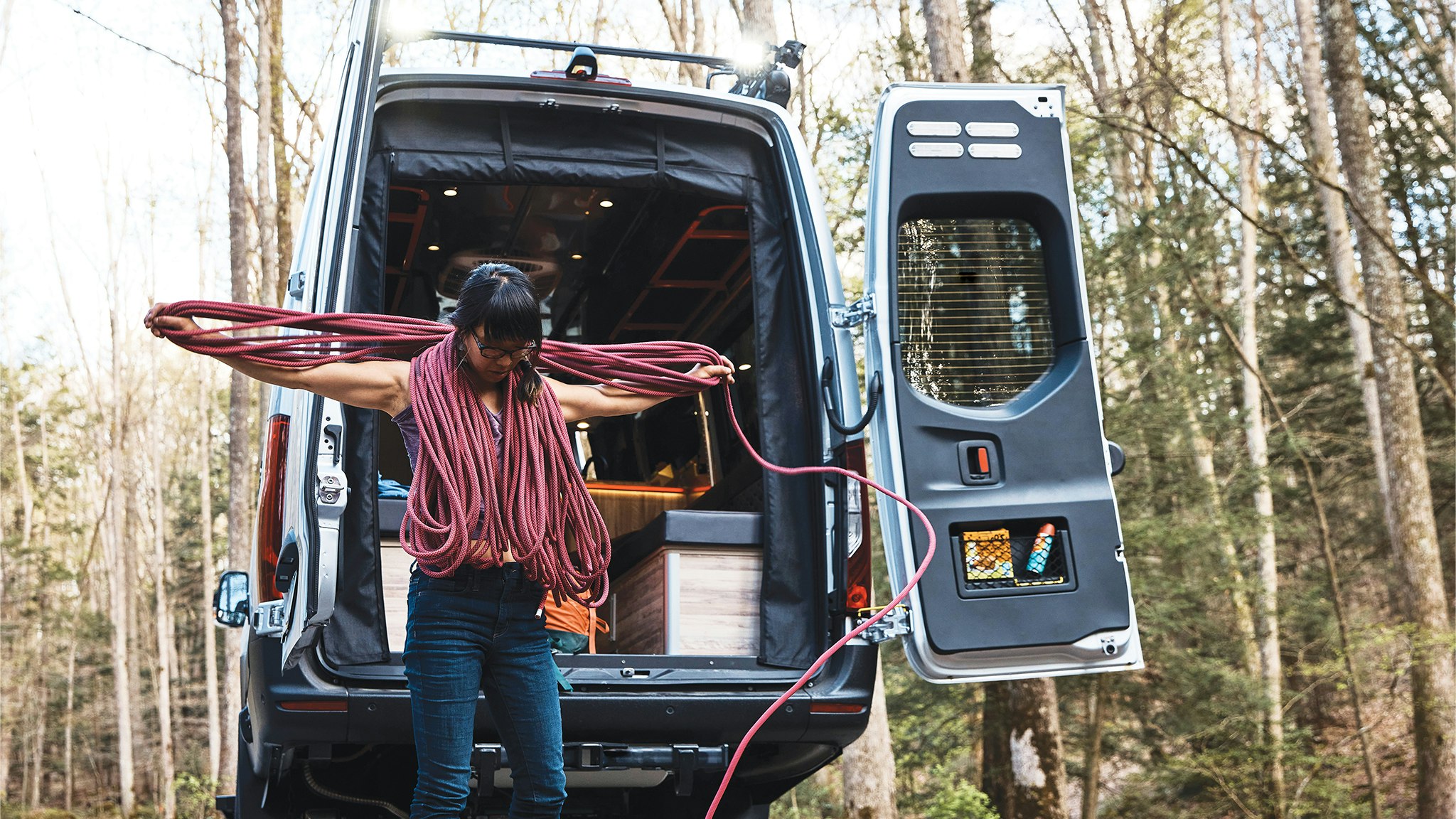A woman getting her rope ready for a climb with her gear in her Airstream 24X Class B Motorhome in West Virgina