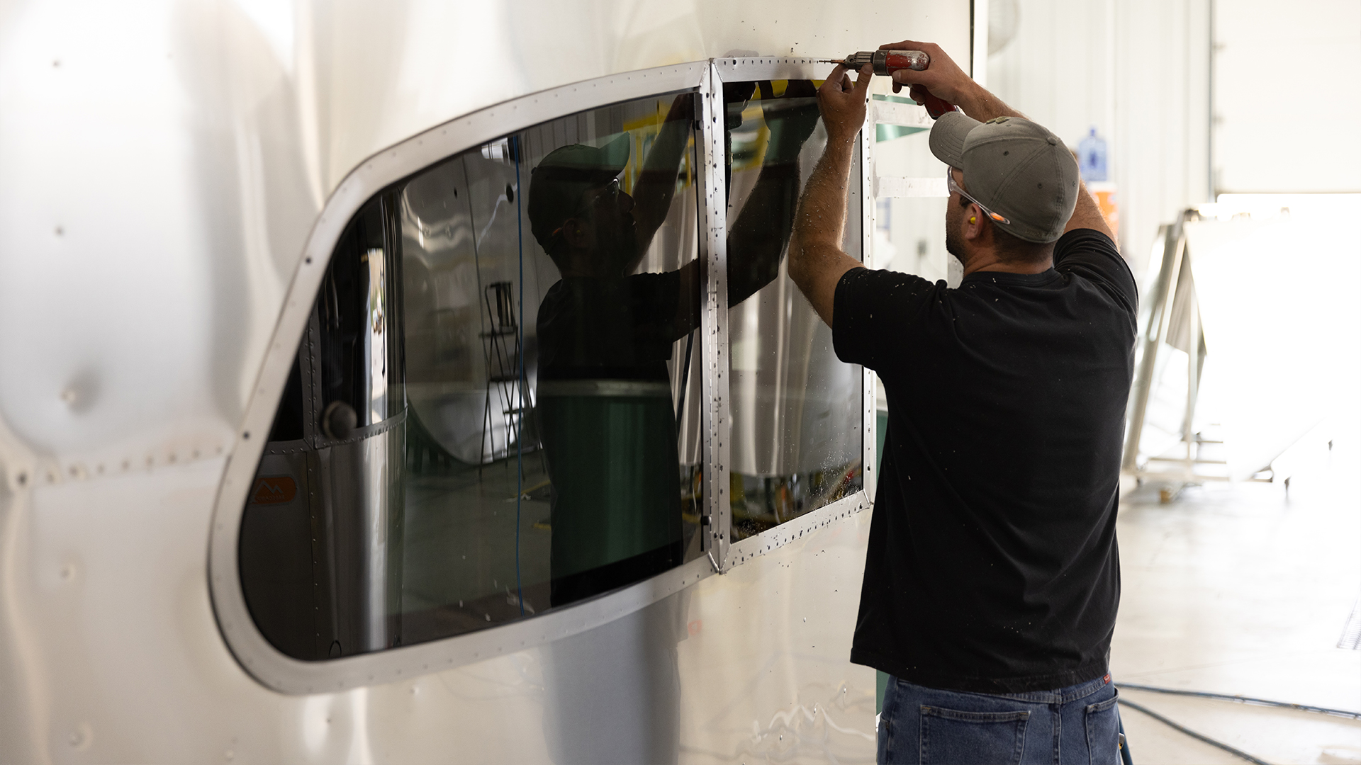 An Airstream employee working on installing the windows of an Airstream Basecamp travel trailer in Jackson Center, OH