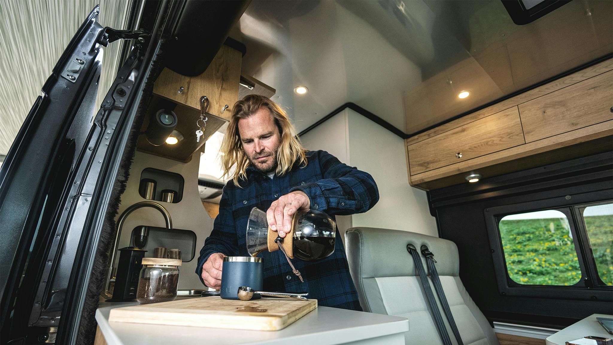 A man making coffee in the galley of his Airstream Rangeline Class B.
