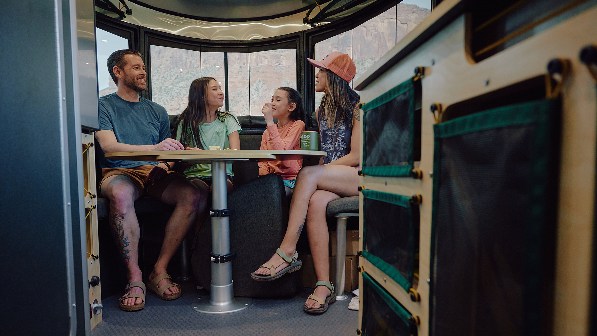 A family sitting at the dinette of their Airstream REI Co-op Special Edition Basecamp 20X.