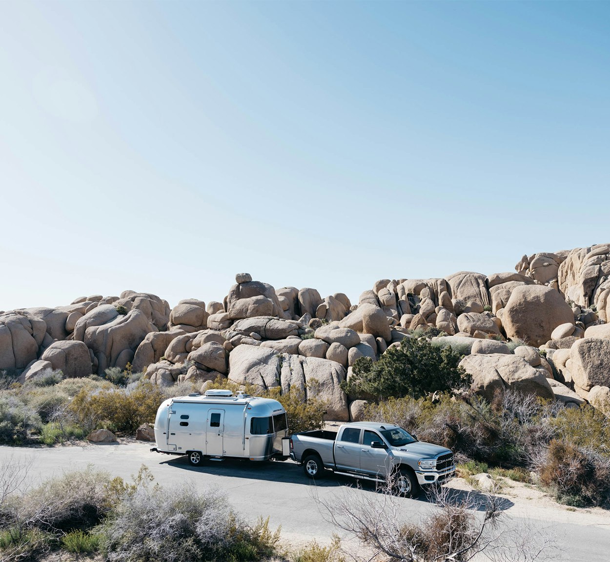 An Airstream caravel travel trailer being towed by a truck in the desert.