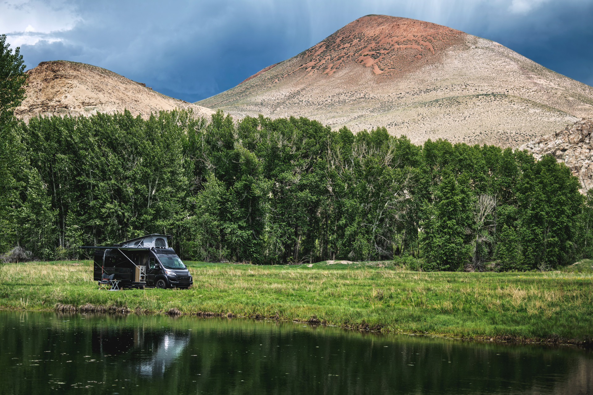 The Airstream Rangeline Class B Motorhome parked in a field with mountains and a lake