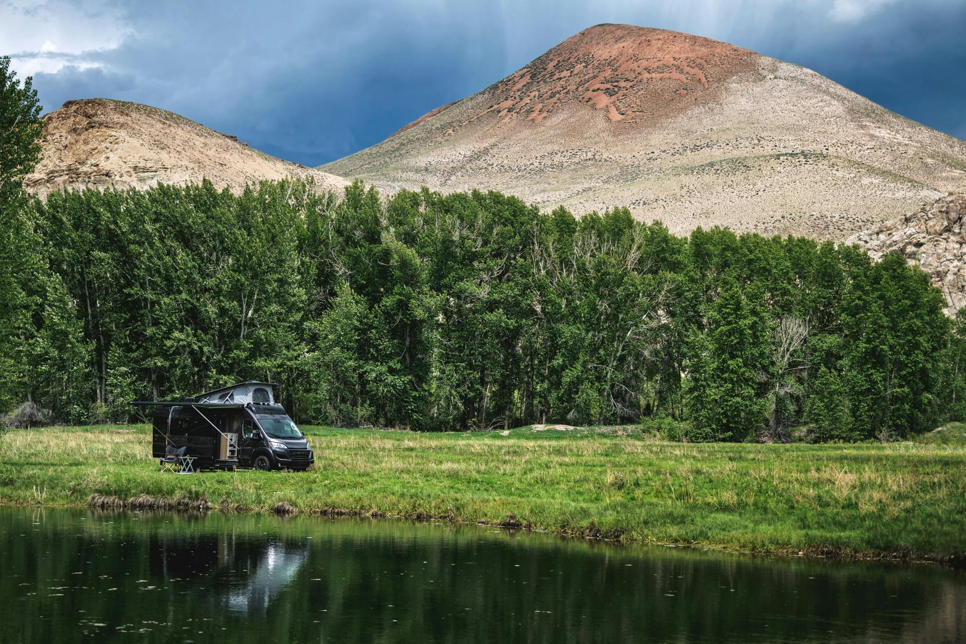 The Airstream Rangeline Class B Motorhome parked in a field with mountains and a lake