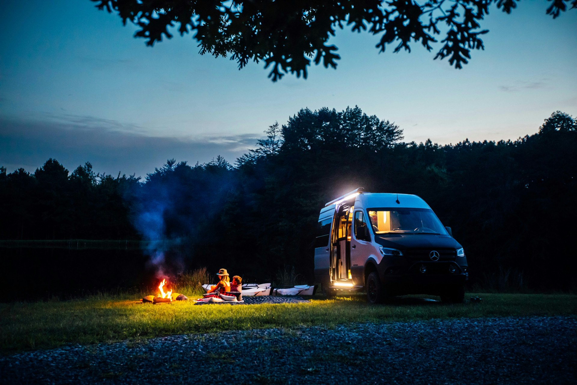 A couple sitting next to a campfire at night next to their Airstream Interstate 19X Class B Motorhome