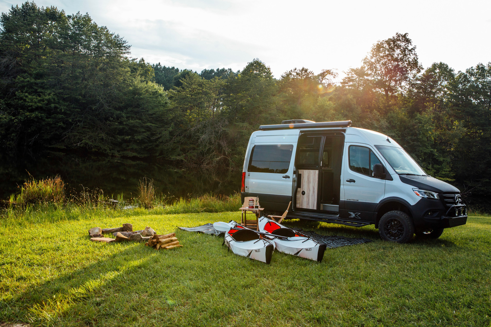 Airstream Interstate 19X Class B Motorhome parked in a field with kayaks sitting next to it